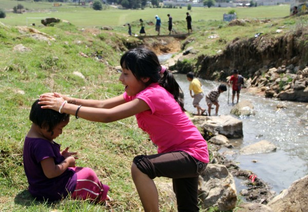 Niñas desplazadas por la violencia  juegan a la orilla de un arroyo, cercano a su refugio en San Cristóbal. Foto: Elizabeth Ruiz