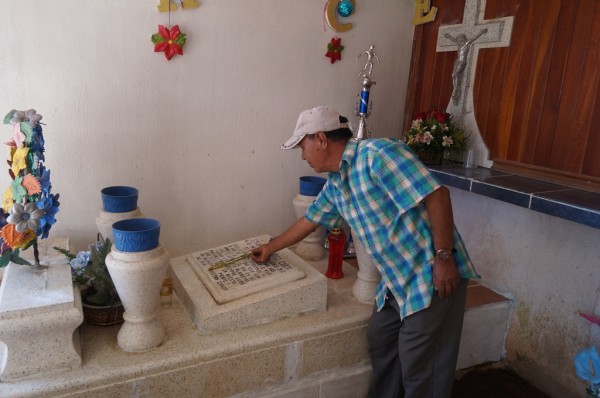 En el panteón del ejido Cristóbal Obregón, don Hilario limpia la tumba de su hijo Edgardo asesinado a los 33 años en junio del 2012. 