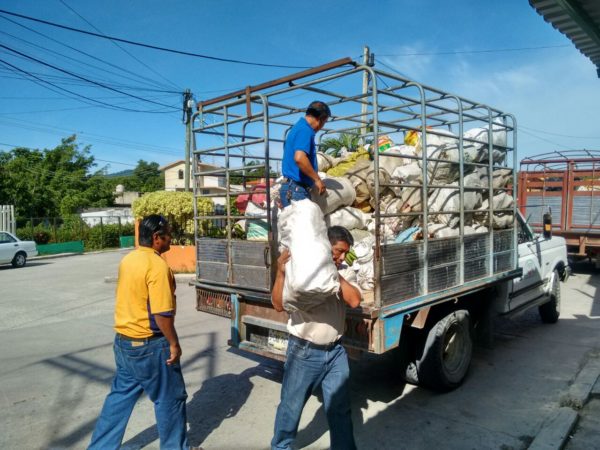 Maestros descargan los costales con alimentos enviados por los zapatistas.