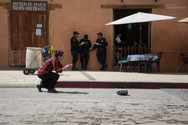 Perita hace una fotografía del espejo de la camioneta, al fondo unos policías leen junto al carro de limpieza de la mujer fallecida.