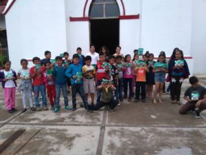 Equipo de difusión repartiendo libros sobre protección civil a niños y niñas de Siltepec.