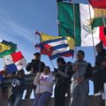 MIGRANTES LEVANTAN BANDERAS DE DIFERENTES PAÍSES DURANTE MISA BINACIONAL CELEBRADA POR OBISPOS DE CIUDAD JUÁREZ Y EL PASO, TEXAS SOBRE EL CAUCE DEL RÍO BRAVO. FOTOGRAFIA: LA VERDAD - ARCHIVO