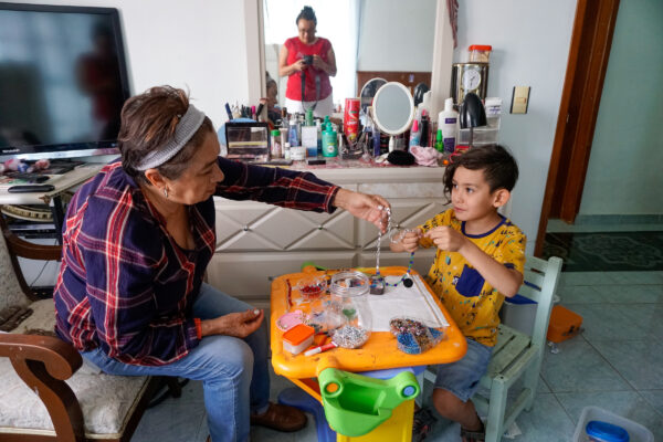 Cosme Damián Peña Suárez del Real y su abuela, Beatriz Islas, hacen pulseras y collares en su casa en Tecámac, México, el 6 de junio de 2023.