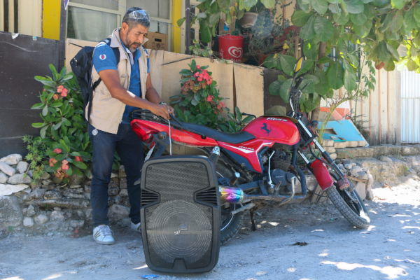 David Teliz Martínez desata un altavoz de su motocicleta para recorrer las calles de la colonia 21 de Septiembre, en las afueras de Chilpancingo de los Bravo, Guerrero, México, el 7 de noviembre de 2023. Teliz recorre las colonias en busca de nuevos alumnos para que continúen sus estudios en el Instituto Estatal para la Educación de Jóvenes y Adultos de Guerrero. Foto: Avigaí Silva Panchito, Global Press Journal Mexico